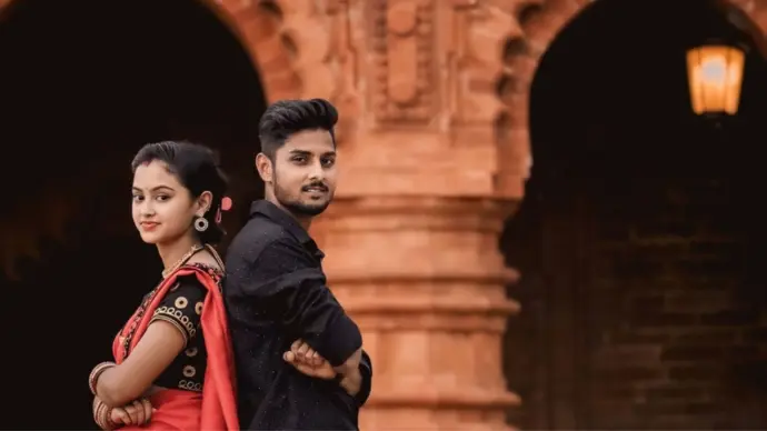 A beautifully captured portrait of a couple standing back-to-back, blending traditional attire with a timeless, cinematic backdrop — showcasing love, culture, and storytelling.