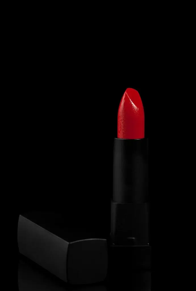A striking close-up of bold red lipstick against a pure black background — capturing elegance, contrast, and high-end product aesthetics.